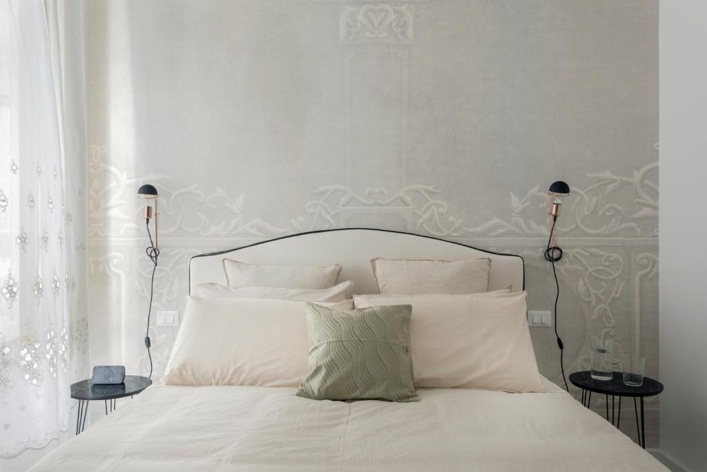 un letto con lenzuola e cuscini bianchi in una camera da letto di Palazzo Ventimiglia a Palermo