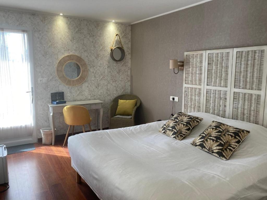 um quarto com uma cama, uma mesa e uma cadeira em Hôtel Des Argousiers em Ambleteuse