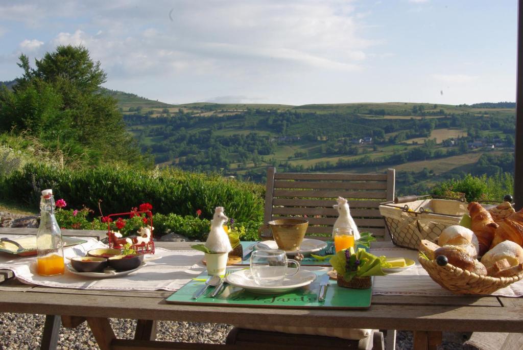 a picnic table with food on it with a view at Chambre d'hotes grange de la bastide in Laveissière