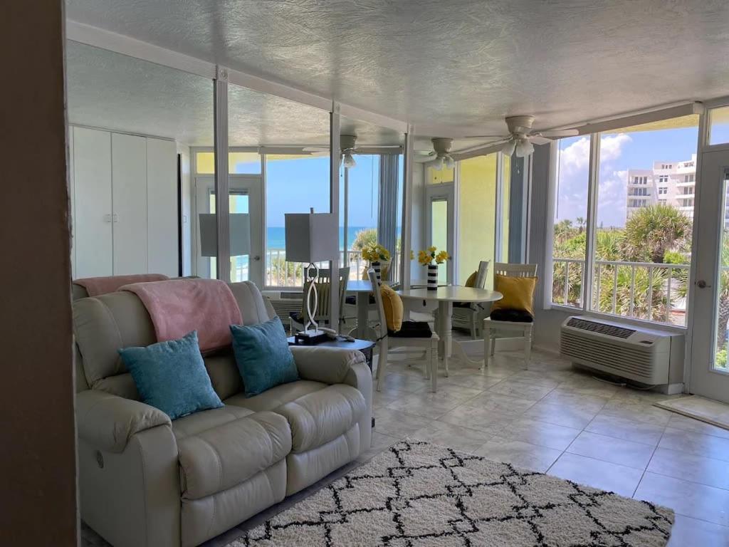 a living room with a white couch and a table at Beach Blessed - Sea View at Symphony Beach Club in Ormond Beach