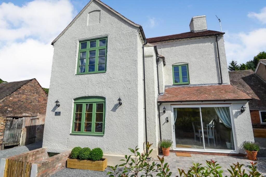 a white house with green windows and plants at The Engine House, 36 Coalford in Ironbridge