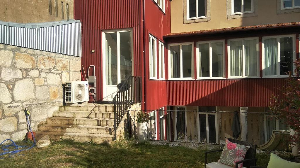 a red house with stairs next to a building at Lusitania Garden Apartment - Jardim Privado in Porto