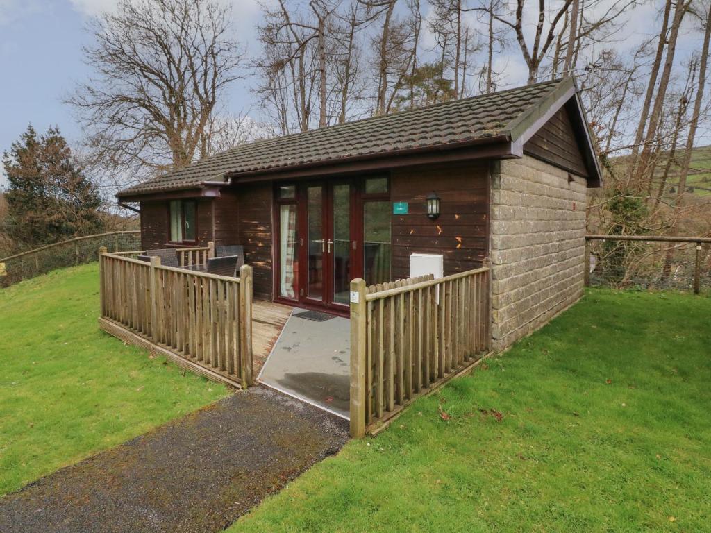 a small house with a wooden fence in a yard at Chalet Log Cabin L6 in Ilfracombe