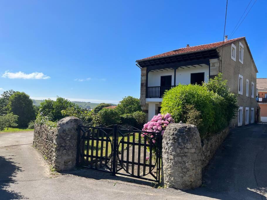 Una casa con una puerta con flores rosas. en Estupenda Casona Rural Montañesa, en Trasvia