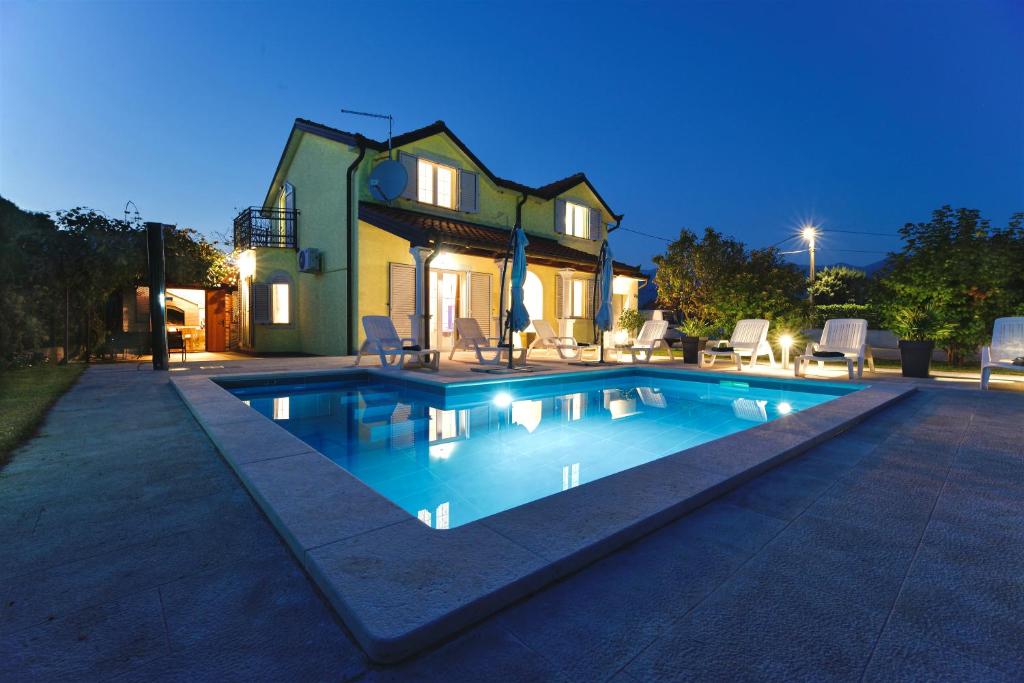 a swimming pool in front of a house at night at Relax House Nizic in Dražice
