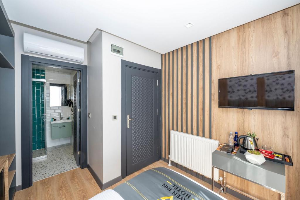 a bedroom with a bed and a television on a wall at Heaven Inn Airport Hotel in Arnavutköy