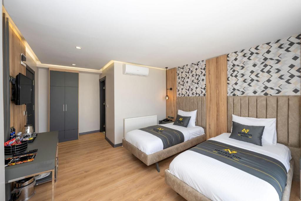 a hotel room with two beds and a desk at Heaven Inn Airport Hotel in Arnavutköy
