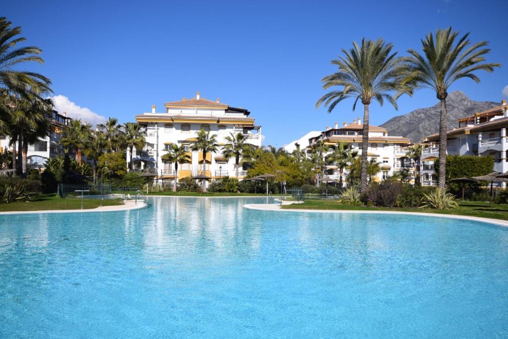 uma piscina com palmeiras e edifícios em Apartman La Concha in Puerto Banus em Marbella