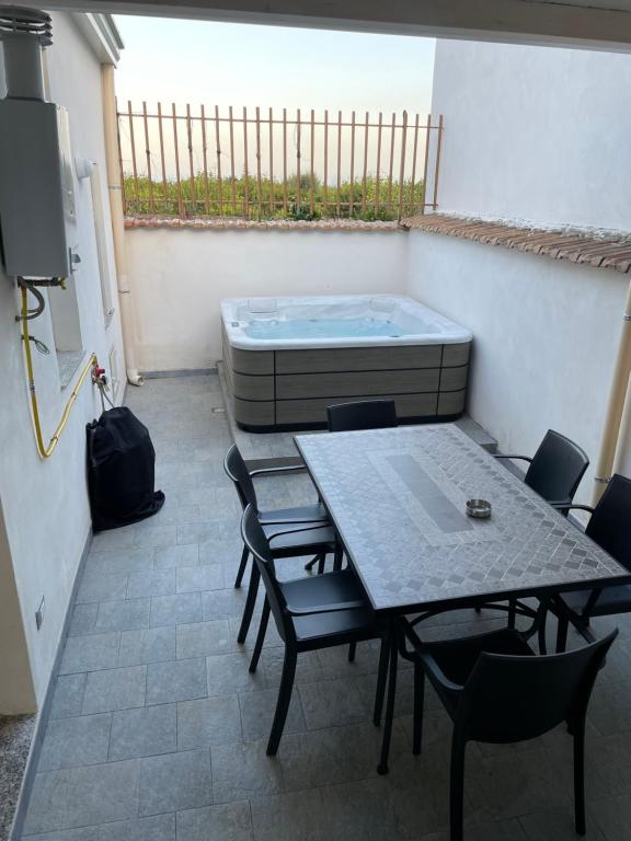 un patio con mesa, sillas y bañera en Daiana House, en Fiumefreddo di Sicilia