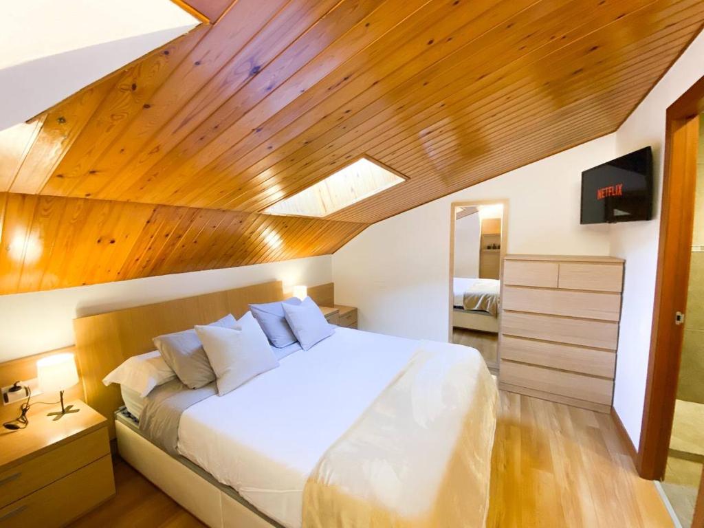 1 dormitorio con cama blanca y techo de madera en Elegante Ático Encamp - FREE Parking Wifi SmartTv - Con altillo y 2 baños completos! en Encamp