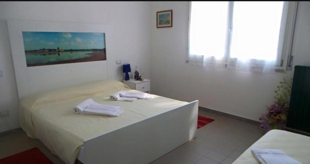 Un dormitorio blanco con una cama con toallas. en TENUTA LA CONFINA, 