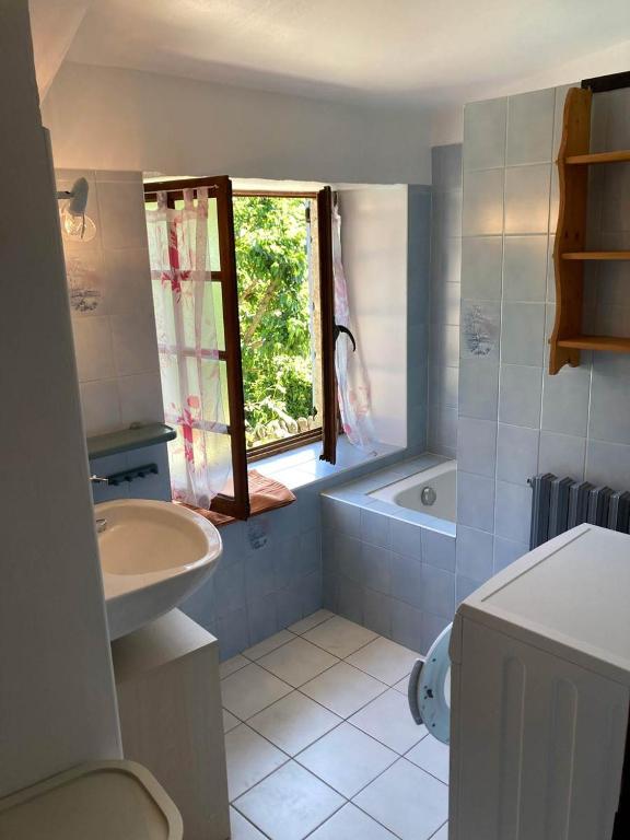 łazienka z umywalką, wanną i oknem w obiekcie Gîte L'hirondelle w mieście Meyrueis