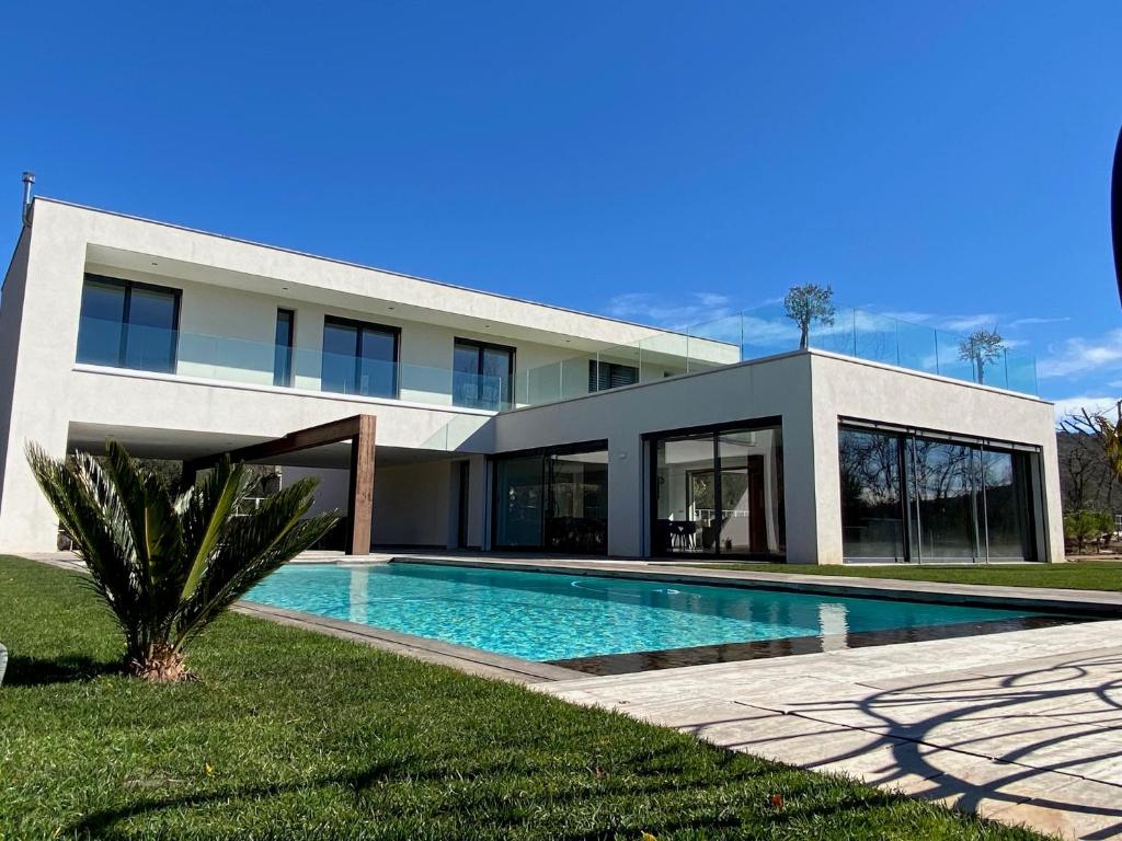 een huis met een zwembad ervoor bij La Villa Blanche in Saint-Cézaire-sur-Siagne