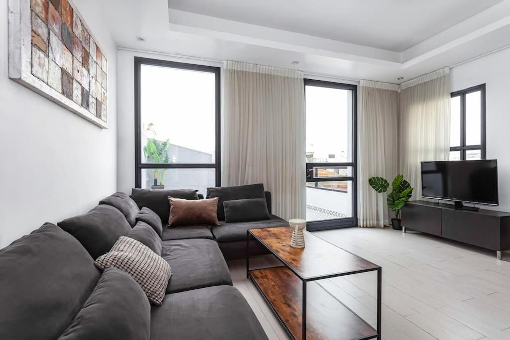 Il comprend un salon doté d'un canapé et d'une télévision à écran plat. dans l'établissement Heart of Tel Aviv, Apartment 7, à Tel Aviv