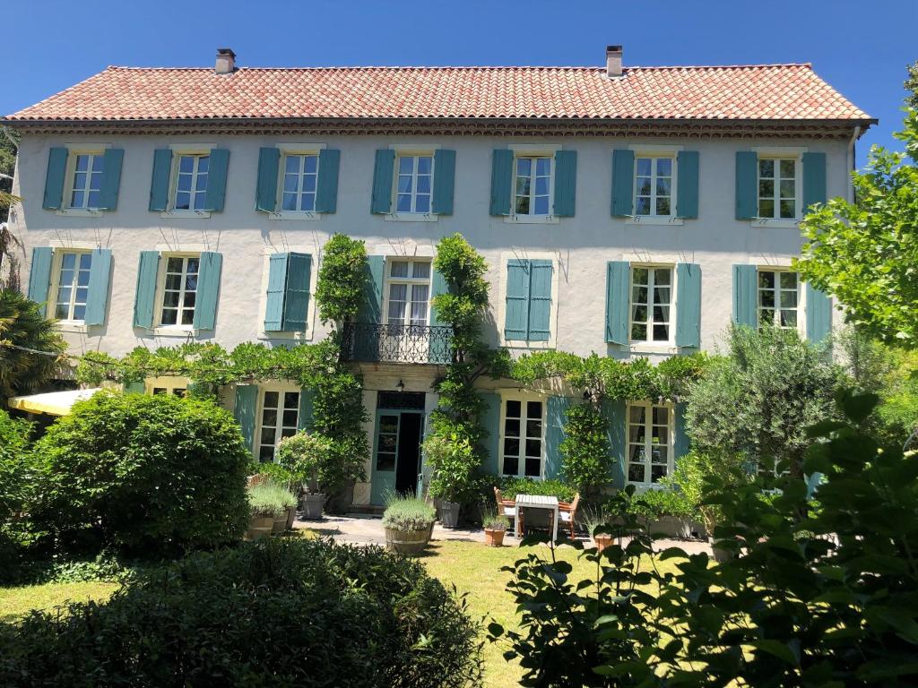 uma casa grande com persianas azuis e um quintal em La Cerisaie - Chambres d'hôtes & gites em Riols