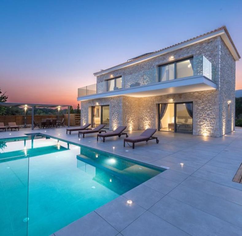 une maison avec une piscine en face d'une maison dans l'établissement Kefalonia Stone Villas - Villa Petros Kefalonica, à Trapezaki