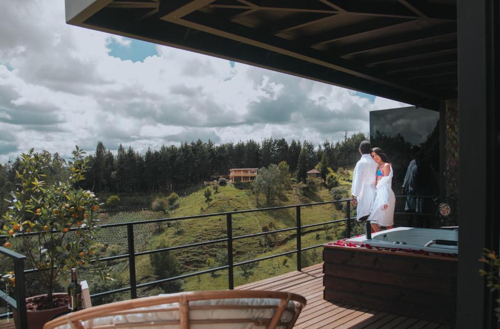 Una novia y un novio parados en el balcón de una casa en Cumbres Luxury Glamping en Guarne