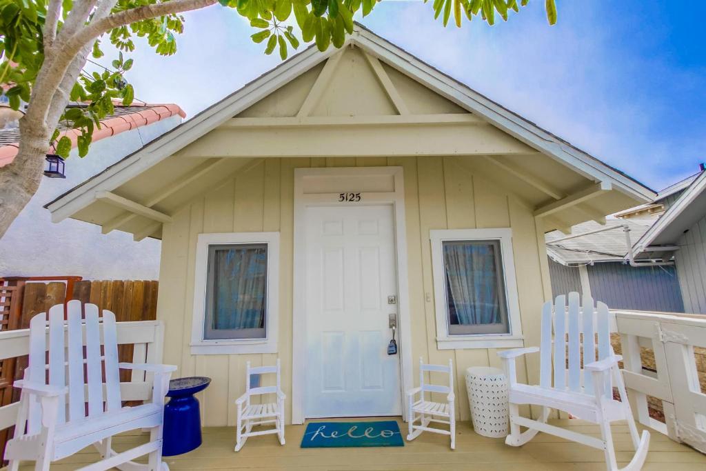 uma pequena casa amarela com duas cadeiras brancas num alpendre em OB Beach Daze 1 em San Diego
