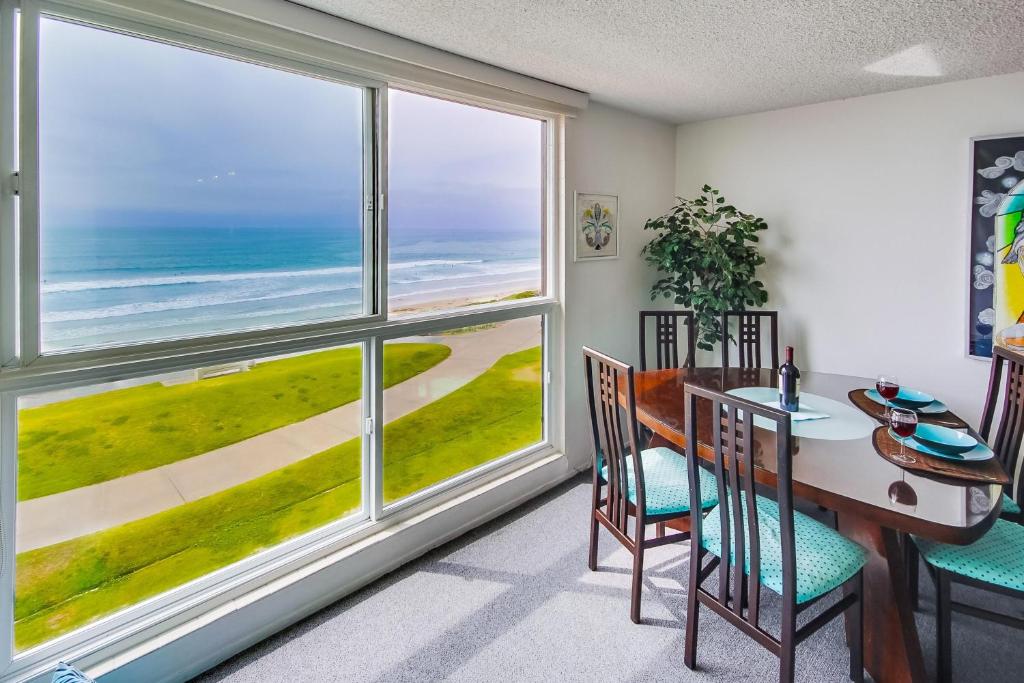 a dining room with a table and chairs and large windows at Beachview Condo in San Diego