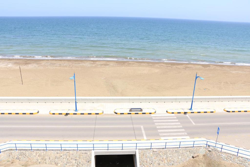 a road next to a beach with the ocean at Marina in Sohar