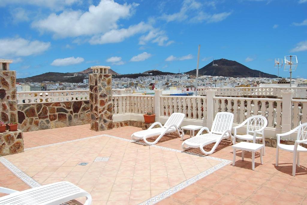 a patio with white chairs and a view of a city at Apartamentos Tinoca in Las Palmas de Gran Canaria