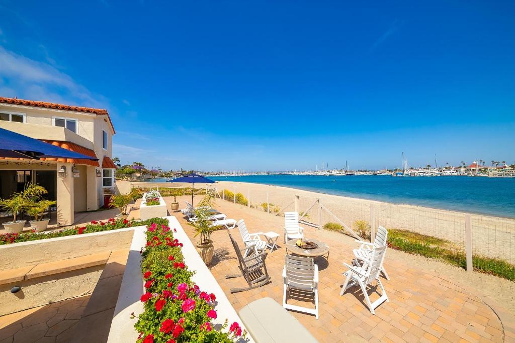 uma praia com cadeiras brancas, mesas e flores em On The Beach Casita em San Diego