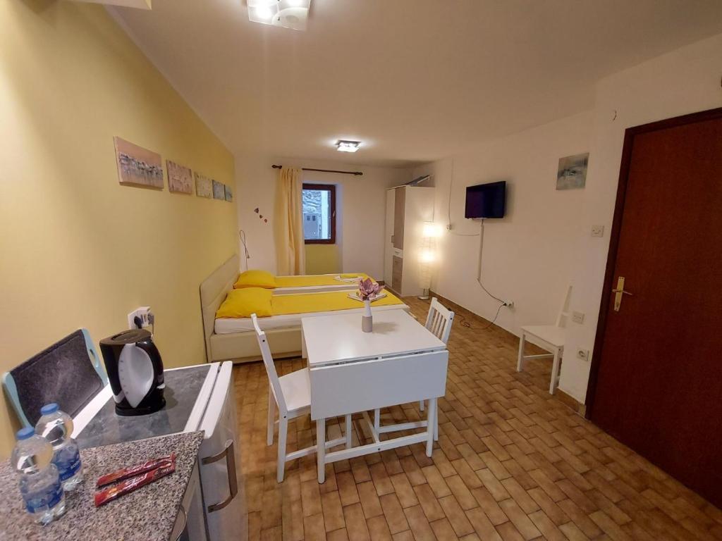 ピランにあるTerra Apartmentsのベッド、テーブル、椅子が備わる小さな客室です。