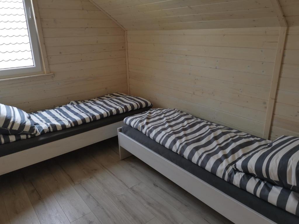 Habitación con 2 camas y paredes de madera. en Brzozowa Przystań, en Okuninka