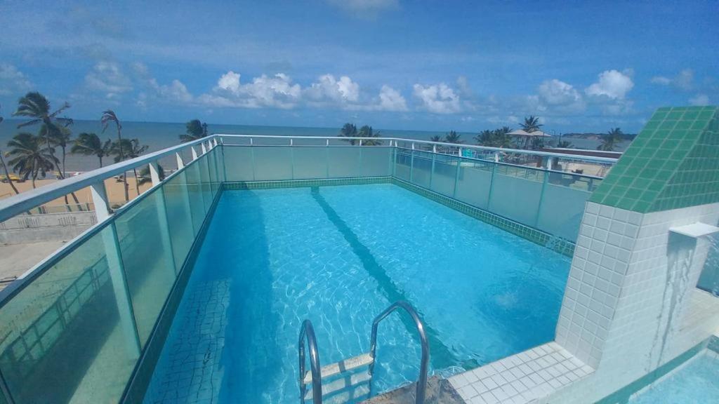 a swimming pool with the ocean in the background at Rede Andrade Solmar in João Pessoa