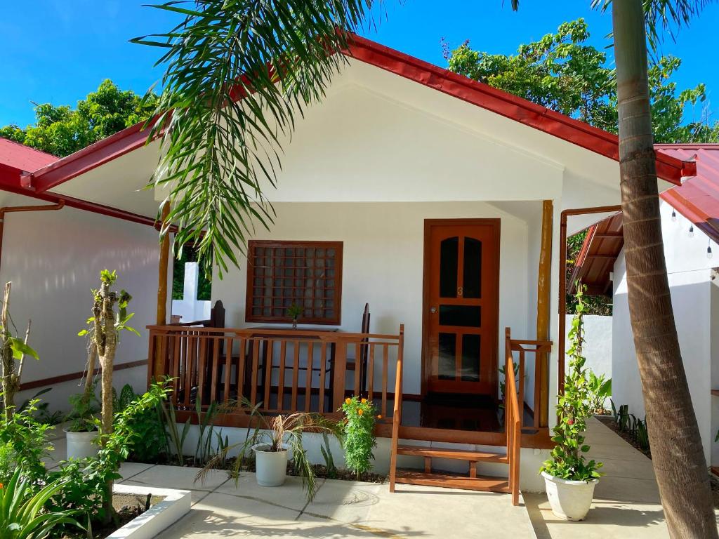 een klein wit huis met een veranda en een palmboom bij CED Villas in El Nido