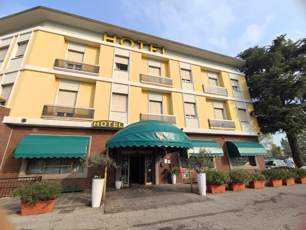 a hotel with a yellow building with a green awning at Hotel Industria in Brescia