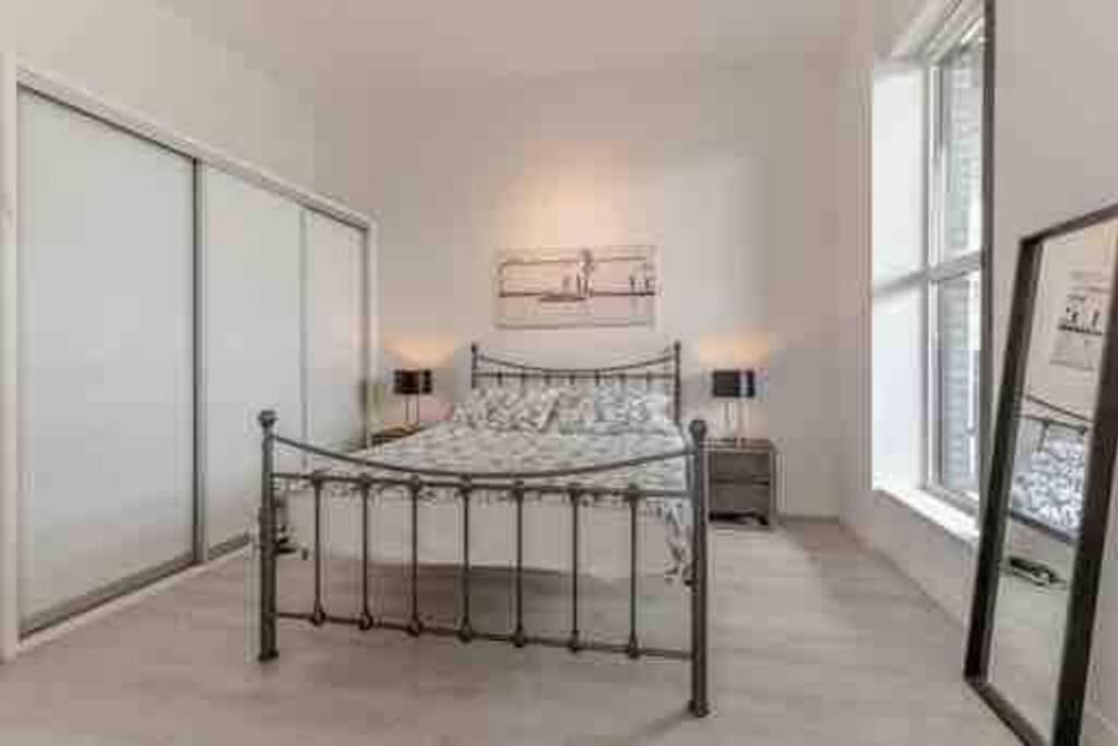 ein Schlafzimmer mit einem Metallbett in einem Zimmer mit Fenstern in der Unterkunft Art deco lodging in London in Hayes