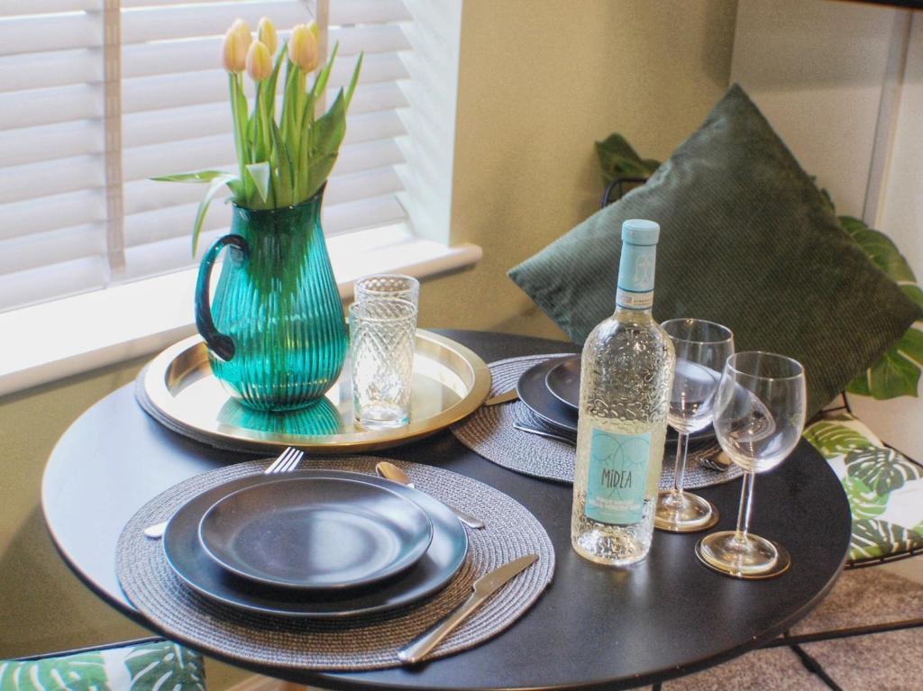 a table with plates and a vase with a bottle of wine at Townhouse with private parking in York