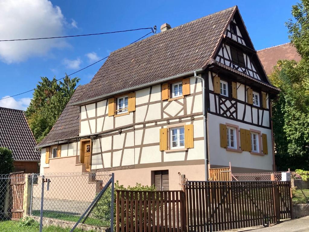 uma casa velha com uma cerca em frente em Maison Alsacienne Typique Gite Weiss em Gunstett