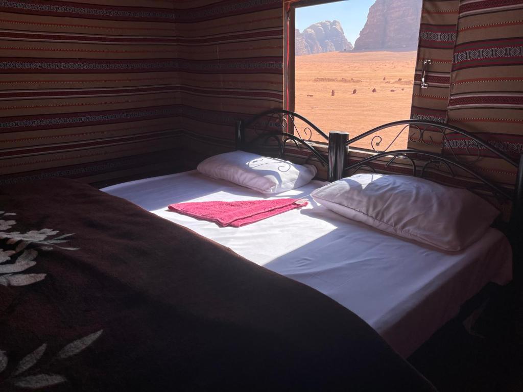 a bed in a room with a view of the desert at Quite bedouin life in Wadi Rum