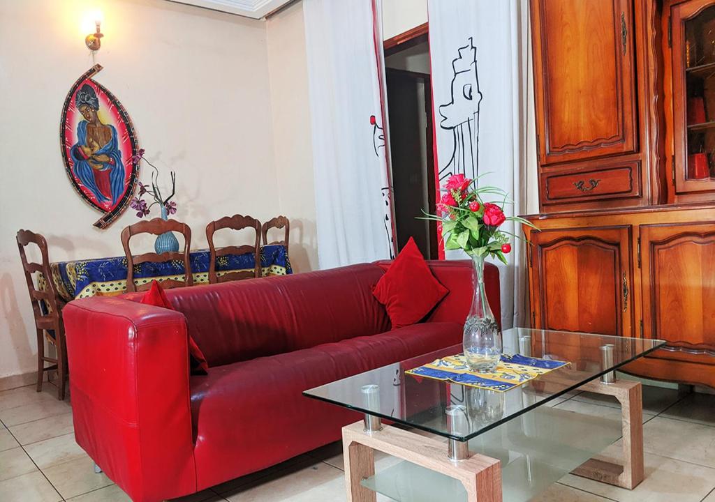 uma sala de estar com um sofá vermelho e uma mesa de vidro em Masso house em Douala
