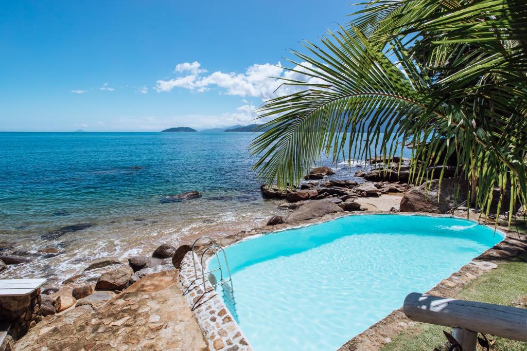 una piscina junto a una playa con el océano en BlowShow Casa I, en Ilhabela