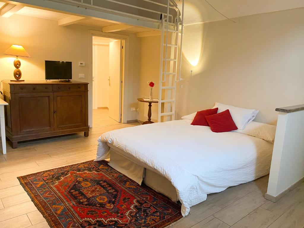 a bedroom with a white bed and a television at Monolocale San Guido in Acqui Terme