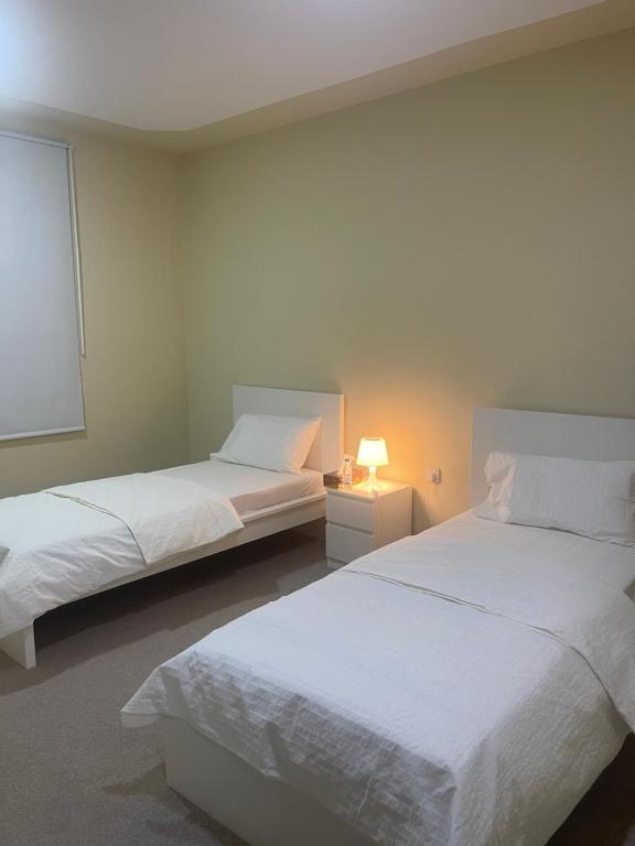 1 dormitorio con 2 camas y lámpara. en معيذر للشقق المفروشه والفندقية, en Doha