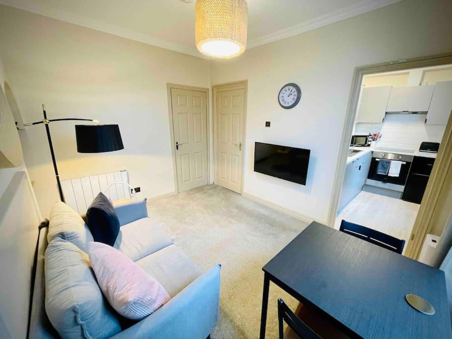 a living room with a couch and a table and a clock at Newly refurbished, central apartment with permit parking in Bath