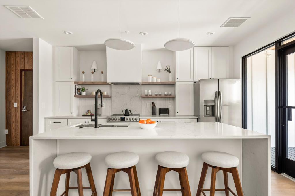 una cocina con una gran isla blanca con taburetes de bar en The Eighteen by Mint House, en Nashville