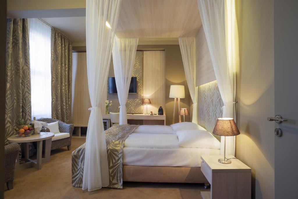 ein Schlafzimmer mit einem Himmelbett und ein Wohnzimmer in der Unterkunft Pytloun Kampa Garden Hotel Prague in Prag