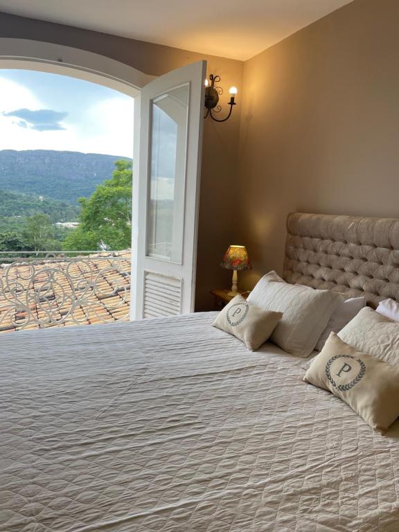 a bedroom with a large bed with a large window at Pousada Pedra Pimenta in Tiradentes
