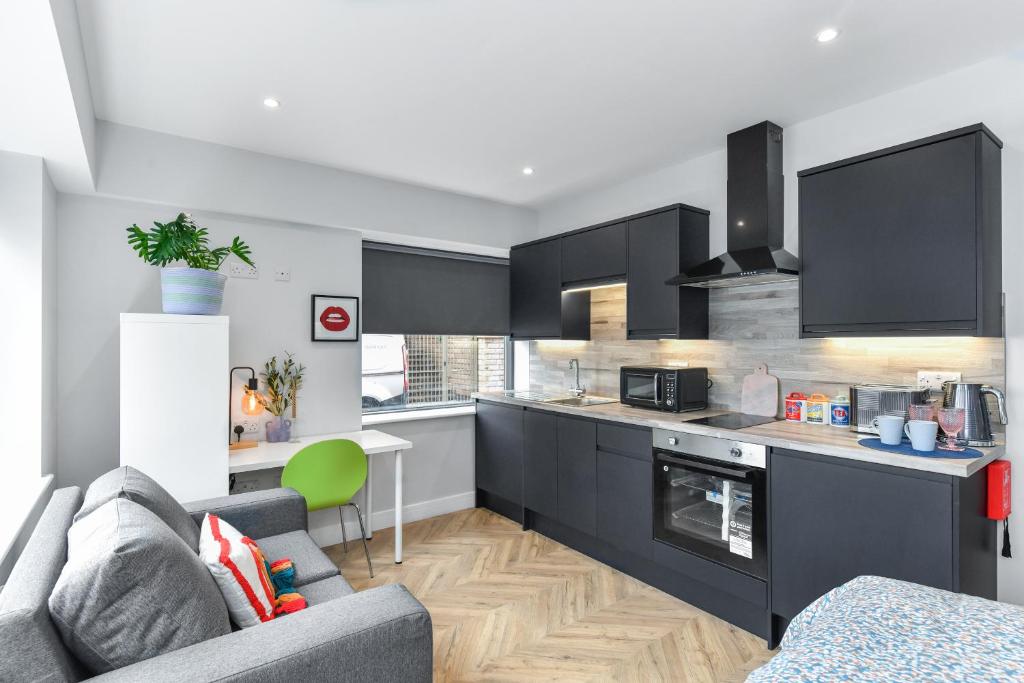 a kitchen with black cabinets and a living room at The Varsity Studios in Nottingham
