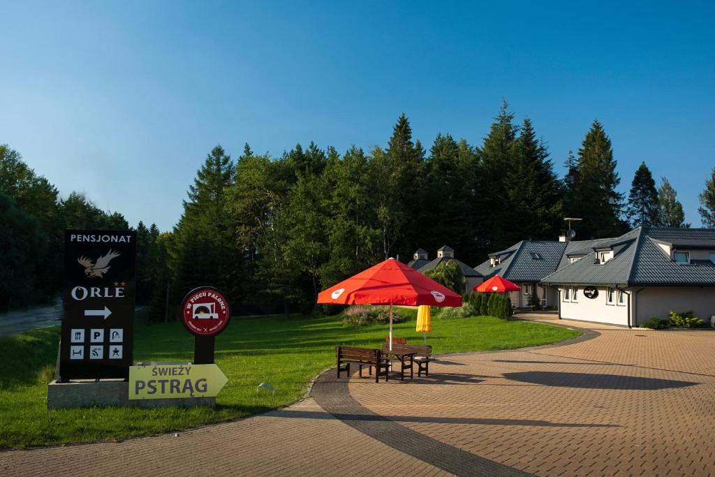 a picnic table with a red umbrella next to a gas station at Pensjonat Orle in Krynica Zdrój