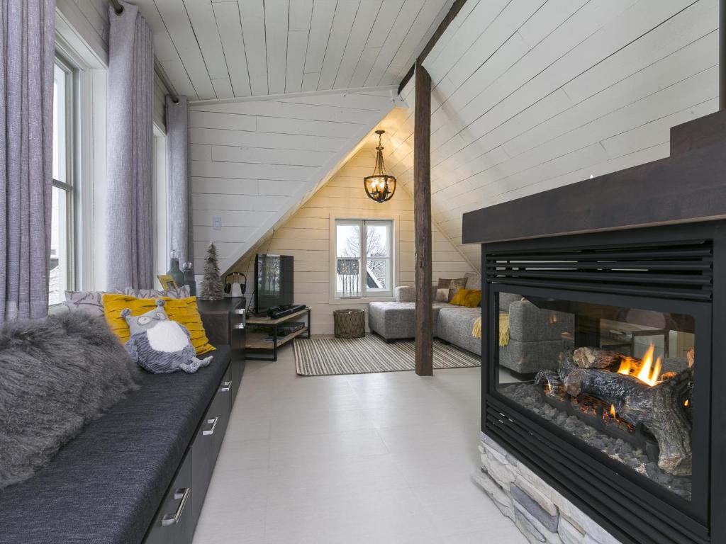 a living room with a fireplace and a couch at 338 - Le Quai des Veuves - Les Immeubles Charlevoix in Baie-Saint-Paul