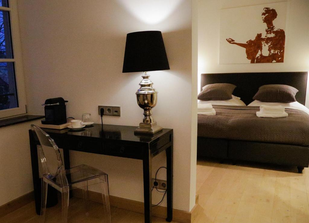 a bedroom with a bed and a desk with a lamp at La Pipistrelle Hotel in Luxembourg