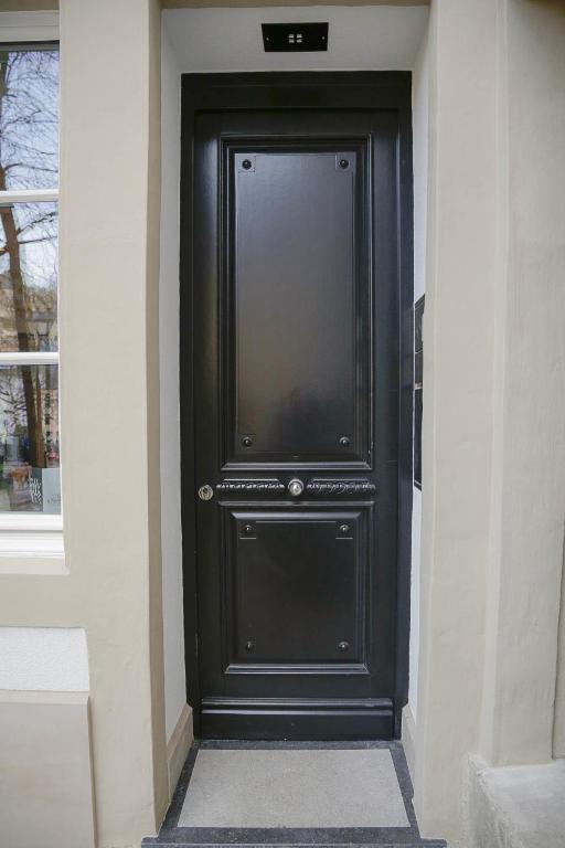 a black door on a building with a window at La Pipistrelle Hotel in Luxembourg