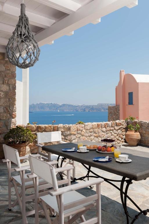 a table and chairs on a patio with a view at Black Gem Villa - Private Heated Jacuzzi & Caldera View in Akrotiri