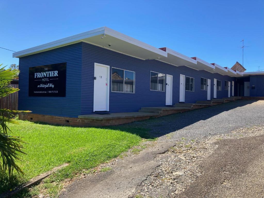 un edificio azul con un cartel en el costado en The Frontier Motel, en Dorrigo